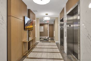 A long hallway with elevators and a painting on the wall